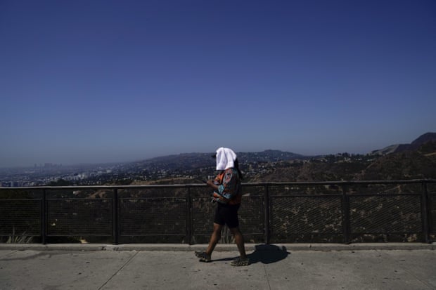 A woman walks on a path with a white towel on her head.