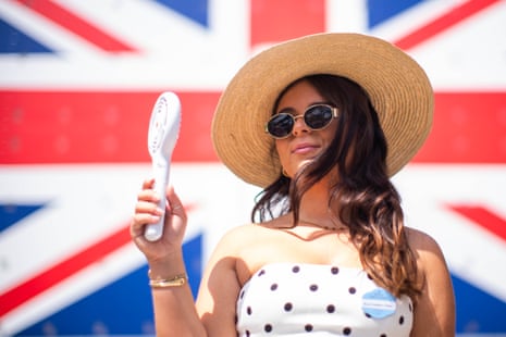 A racegoer uses a hand-held fan in front on day five of Royal Ascot.