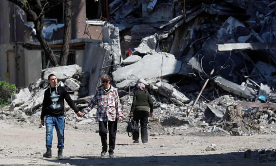 People walk past a destroyed building in Mariupol, Ukraine.