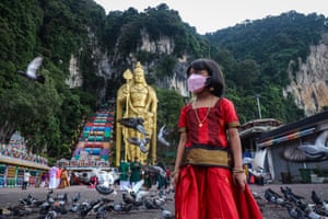 Selangor, Malaysia. A girl arrives at Batu Caves temple for Diwali celebrations. As Malaysia gradually eases its Covid restrictions, religious activities and prayers in temples are allowed only for fully-vaccinated individuals, with mask-wearing and social distancing measures in place