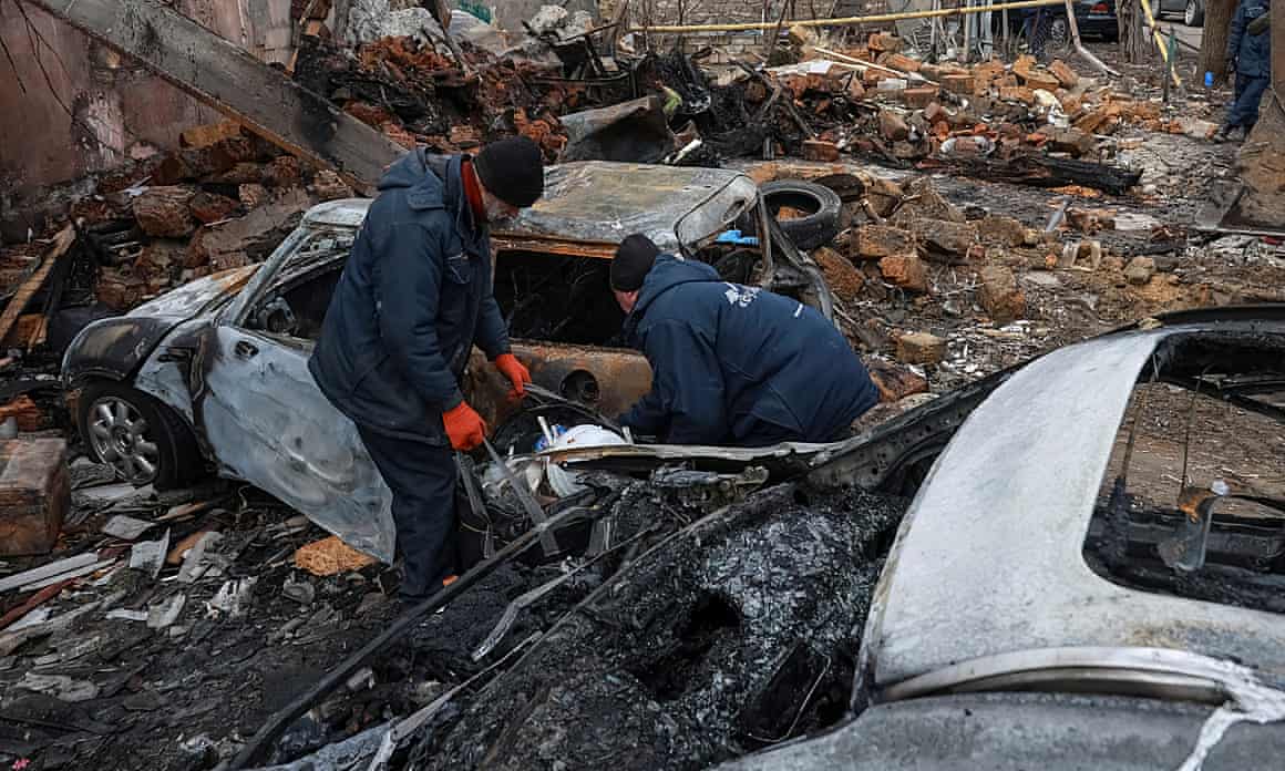 Two people sifting through wreckage