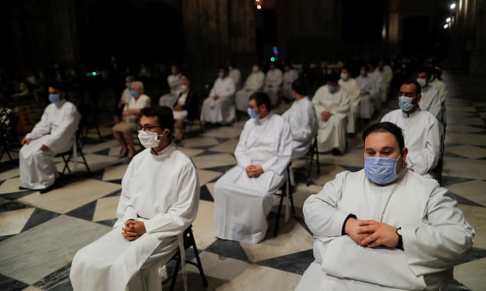 Acolytes wear protective face masks as they attend a funeral mass for the coronavirus victims at the cathedral in Seville.