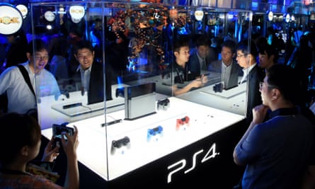 Visitors and media reporters ogle a PS4 game console during the Tokyo Game Show in 2013.