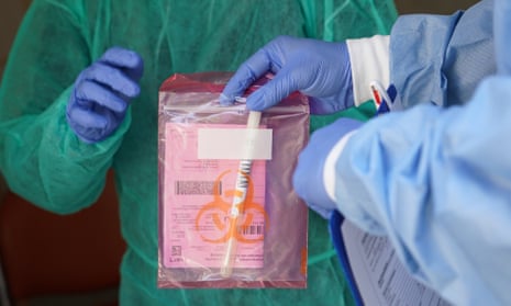 Medical staff seal a bag containing a swab sample from a person seeking a test for possible Covid-19 infection in Berlin.