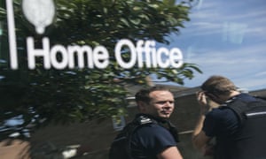 Immigration Enforcement officers are reflected in their vehicle as they raid a property to detain suspected illegal immigrants.