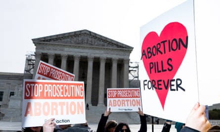 people outside hold up signs with messages such as ‘abortion pills forever’ and ‘stop prosecuting abortion’