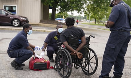 paramedics standing around a man in a wheelchair
