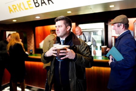A racegoer carries his pints of Guinness at Cheltenham.