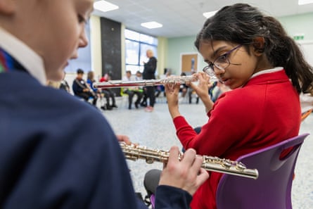 Two young children learning to play flutes