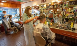 A hairdresser wearing a face mask cuts the hair of a customer, also wearing a face covering, in Dublin as hairdressers reopened in Ireland on 29 June