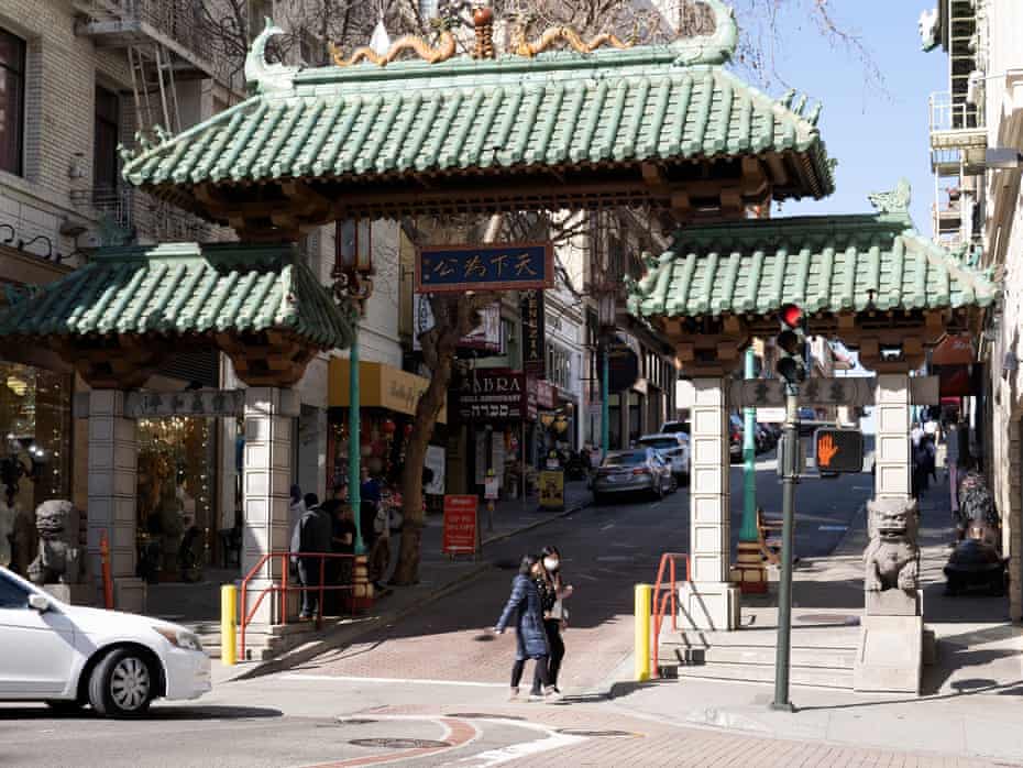 People wear protective masks while crossing the street at the entrance to a largely deserted Chinatown in San Francisco on Wednesday.