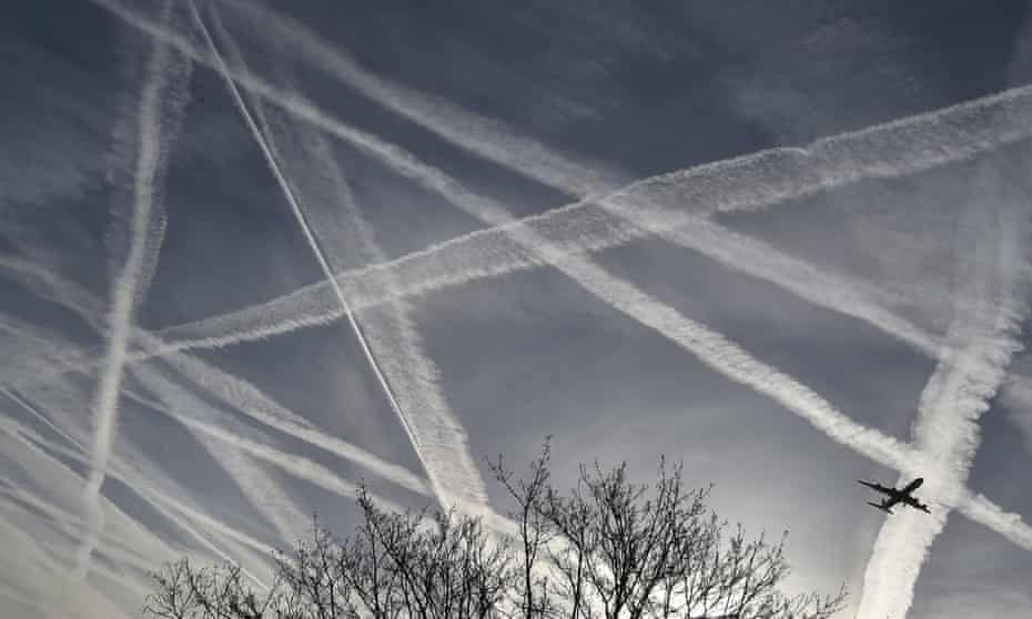A passenger planes flies from Heathrow airport in London as the sky above is crisscrossed by contrails.