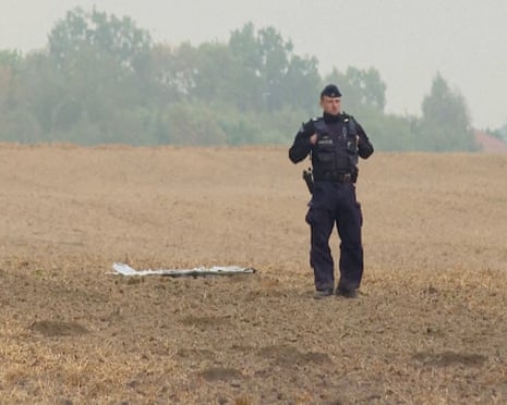 A Polish police officer stands near a unmanned aerial vehicle (UAV) fragment, after Russian drones violated Polish airspace during an attack on Ukraine and some were shot down by Poland, in Cześniki, Lublin Voivodeship, Poland.