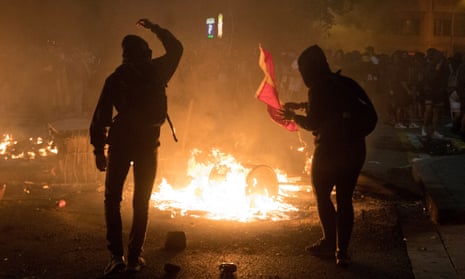 Protesters throw a Spanish flag into the flames