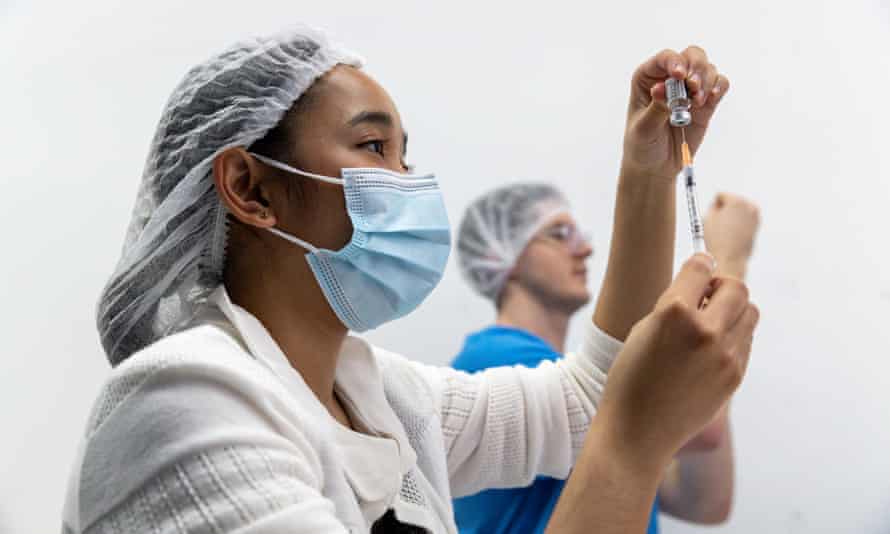 Health care workers fill syringes with the Pfizer vaccine