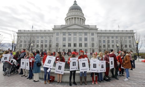 Women dressed in red and holding signs with photos of their local lawmakers are gathered at the Utah state capitol for a Day Without a Woman protest to remind legislators they’re closely watching how they handle women’s issues Wednesday, March 8, 2017, in Salt Lake City. (AP Photo/Rick Bowmer)