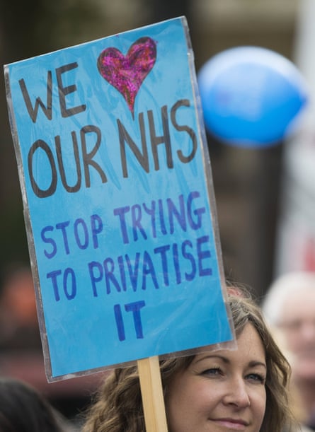 A woman holds a “We love our NHS” placard.