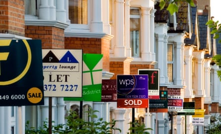 A row of Victorian terraced houses all with estate agent signs outside them