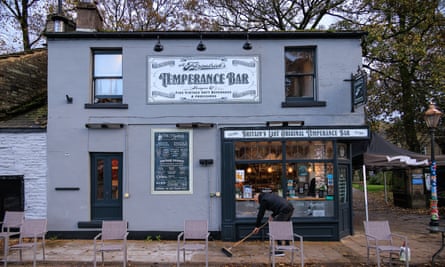 Un homme balaie le trottoir devant le bar Temperance de M. Fitzpatrick à Rawtenstall.