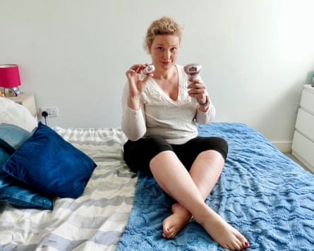 The writer sits on her bed and holds up the Philips Lumea 9900 and one of its attachments