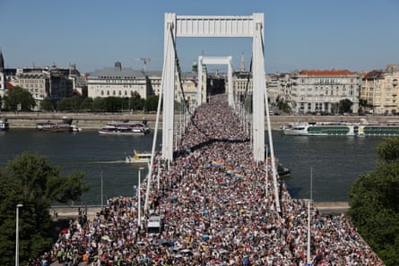 Thousands of people crowd on to a bridge over a river