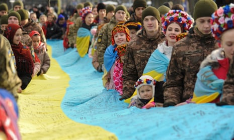 Ukrainians hold a national flag signed by the commander-in-chief Valerii Zaluzhnyi and 1,447 Ukrainian soldiers, in the western city of Lviv, as Ukraine celebrates the anniversary of the unification of east and west in 1919.
