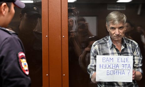 Alexei Gorinov holds up a sign reading ‘Do you still need this war?’ as he is held inside a glass cell in court on Friday