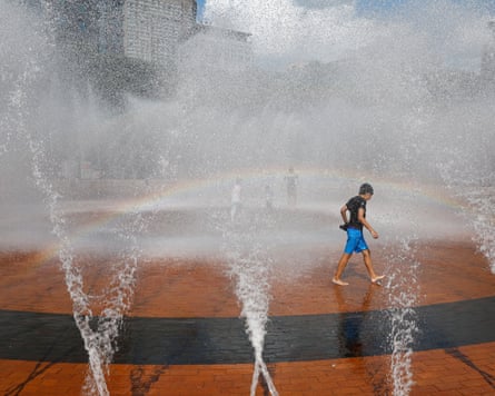 A boy plays walks among spraying water