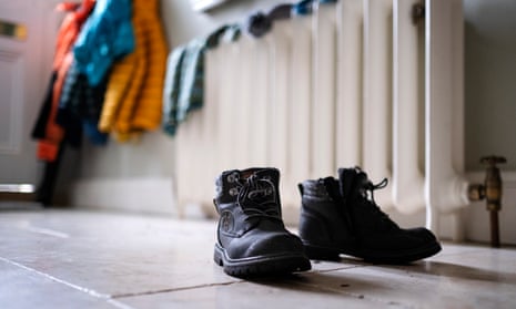 Warm clothes alongside a radiator with boots in the foreground