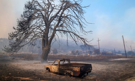 A damaged car stands in front of a burned tree near Loutraki, 80km west of Athens