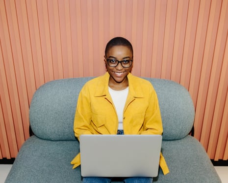 Woman in bright yellow shirt using laptop and smiling