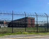Barbed wire fence along grass with brick building behind it