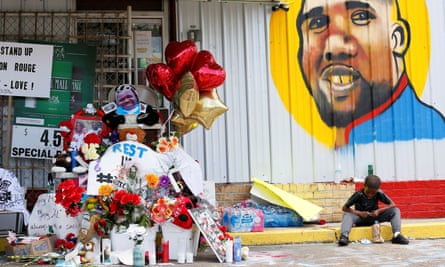 A boy sits next to a makeshift memorial outside the Triple S Food Mart where Alton Sterling was fatally shot by police in Baton Rouge, Louisiana.