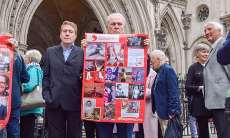 Man holding photos of children with birth defects outside the high court in London