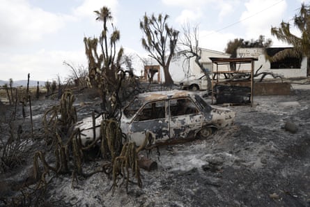 A burnt-out car in a scorched landscape