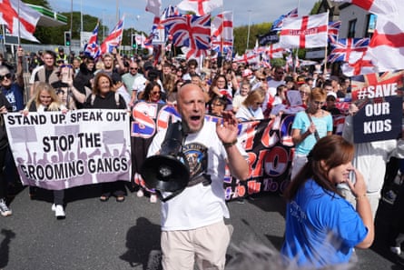 People at an anti-immigration march in Portsmouth waving union and St George flags and with placards.