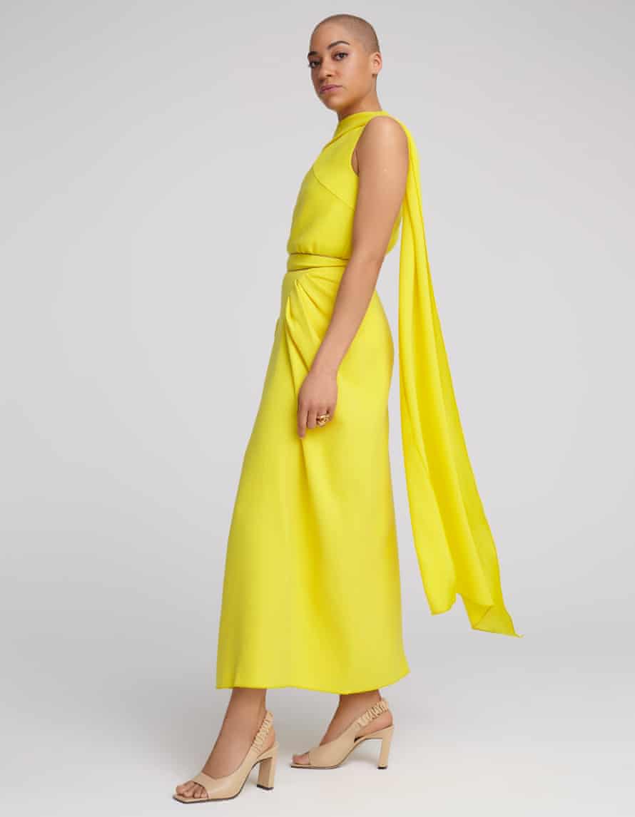 Actor Cush Jumbo in yellow top and skirt against grey background