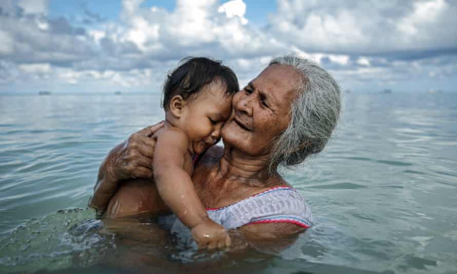 Suega Apelu bathes a child in the lagoon on 28 November 2019 in Funafuti, Tuvalu
