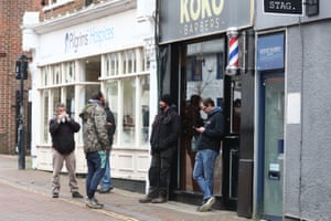 Customers wait to enter a barbers shop in Ashford, Kent, on the first day of reopening following the further easing of lockdown restrictions.