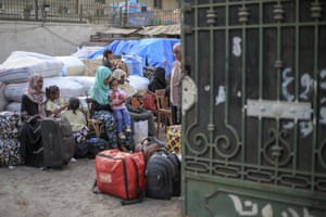Family sitting outside on wooden chairs among suitcases