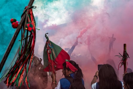Batons with ribbons held against a sky filled with coloured smoke at the funeral of José Albeiro Camayo