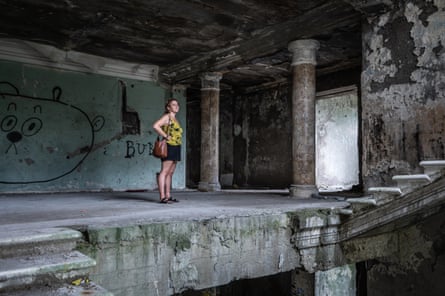 A woman surveys the pillared entrance of an abandoned Soviet-era sanatorium