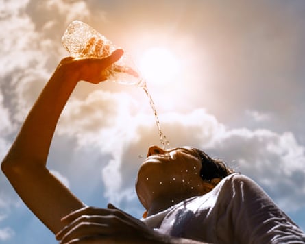 Young woman drinking water under the summer sun.