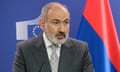 Nikol Pashinyan speaking at a press conference with the Armenian flag behind him.