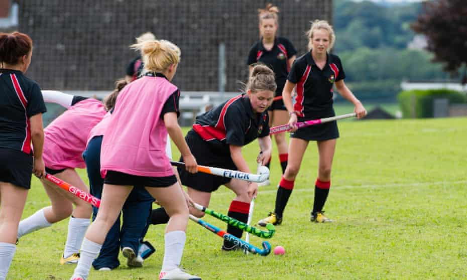 Teenage girls playing hockey outdoors at a secondary comprehensive school in Wales
