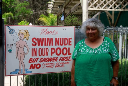Miriam Margolyes next to a sign reading "Swim nude in our pool"