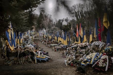 Алея от гробове, покрити с цветя и украински знамена, поставени зад тях