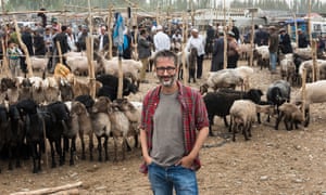 David Baddiel standing with the goats touring Kashgar Sunday livestock market, Xinjiang Region, China.