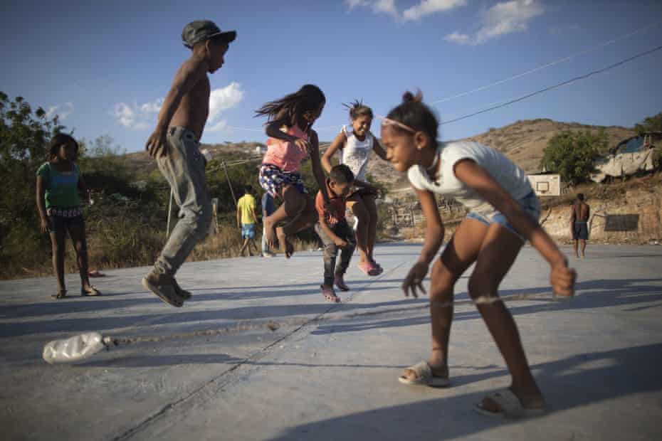 Children jump a rope as they play at a court close to the Pavia garbage dump in Barquisimeto, Venezuela, 3 March 2021