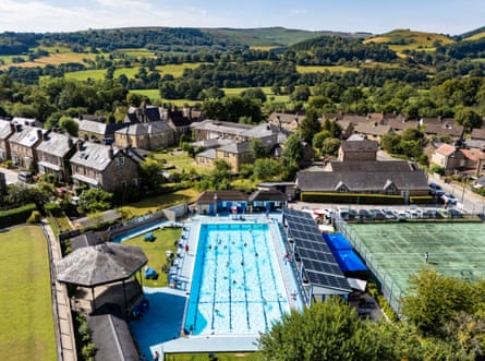 Overhead shot of an outdoor swimming pool surrounded by countryside and a small village